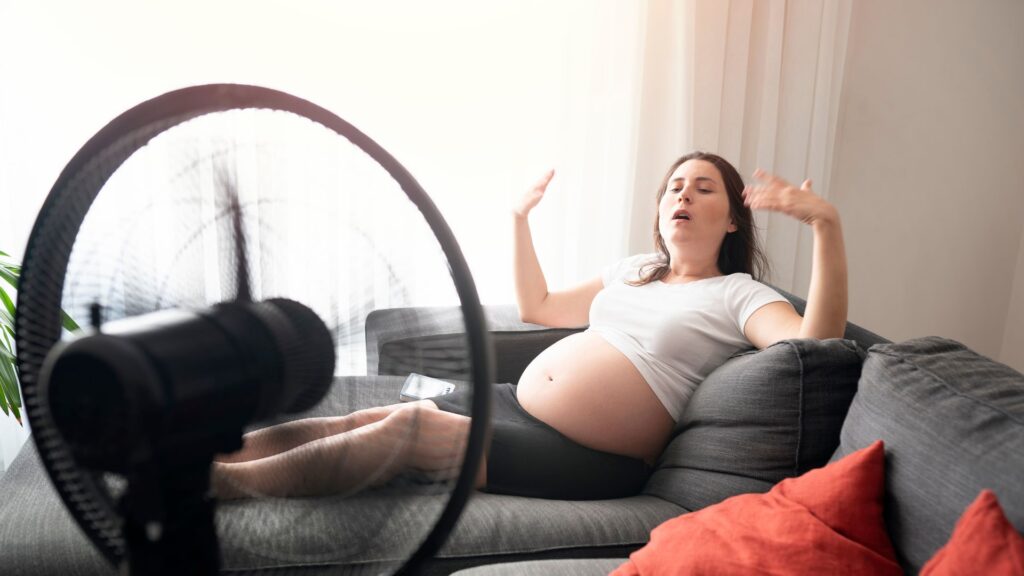 Gestante ao ventilador em um dia quente para se manter hidratada durante a gravidez”